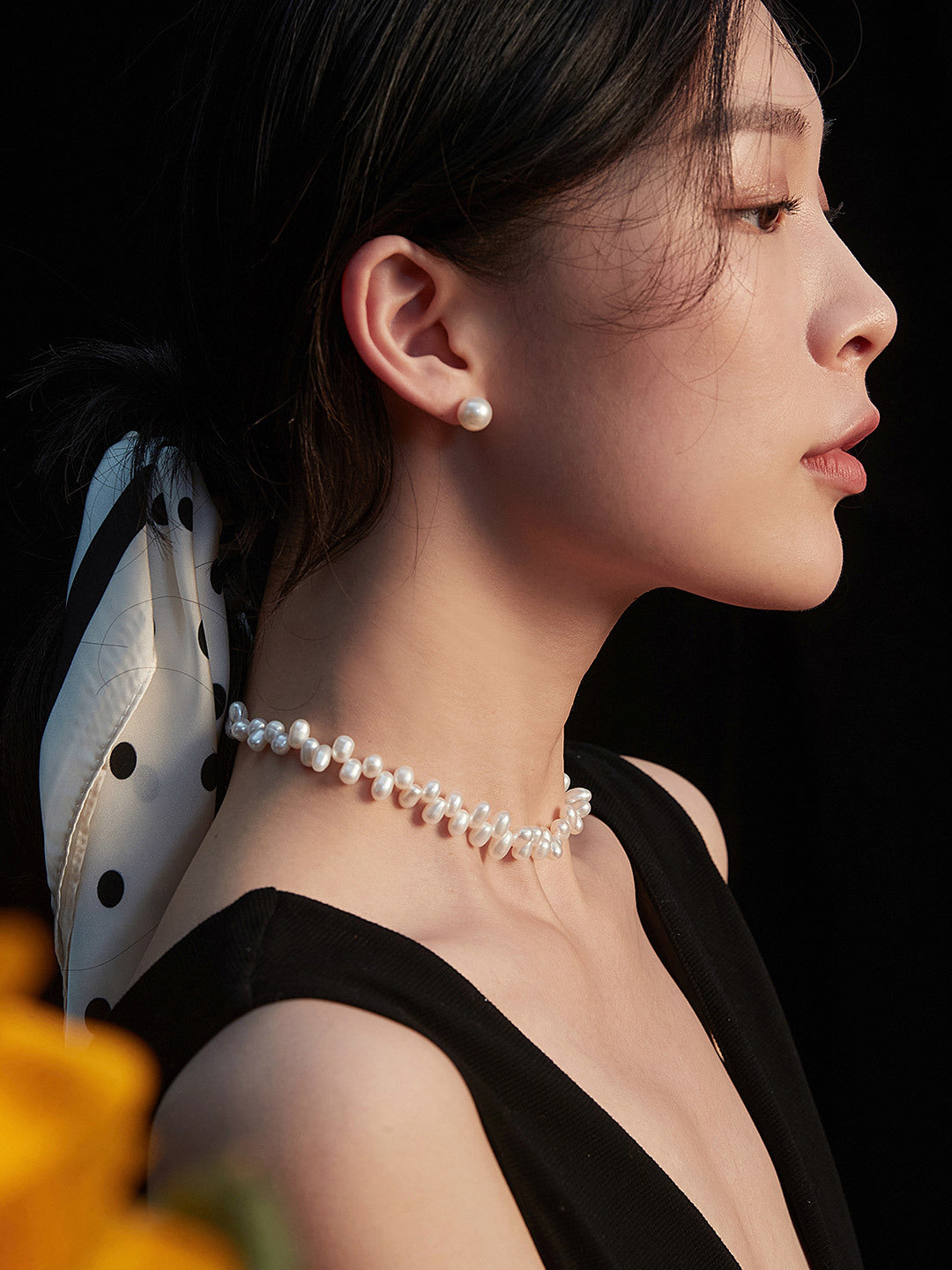 A woman models a chic pearl choker featuring a lovely flower, emphasizing her elegance and unique sense of style.