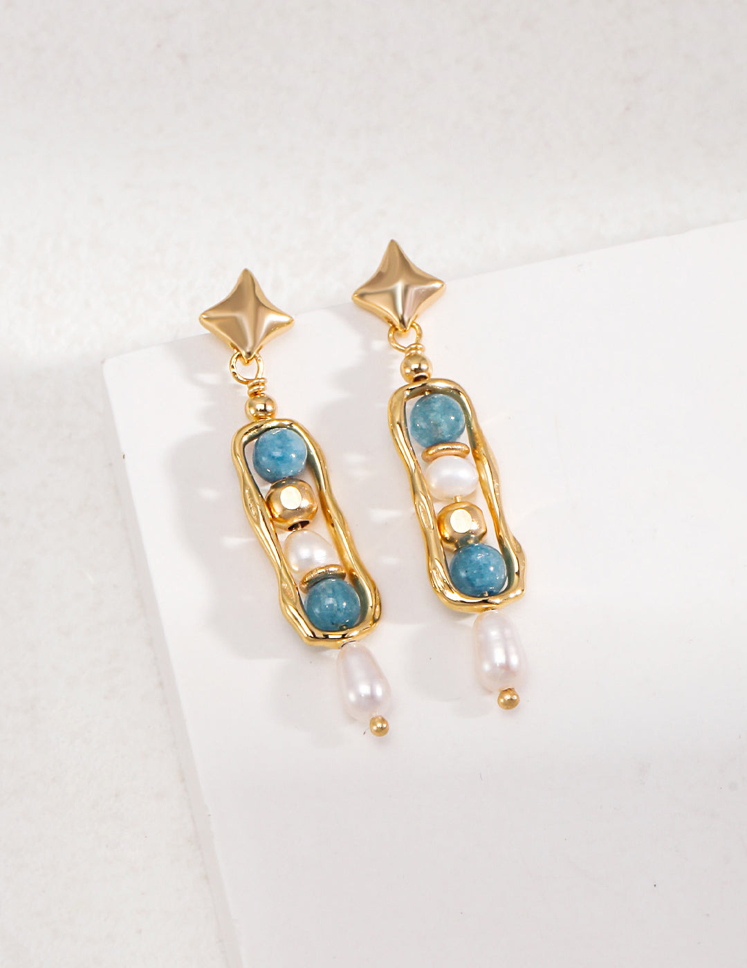 Gold and blue earrings with pearls and beads, featuring unique gemstones, create a stunning accessory.