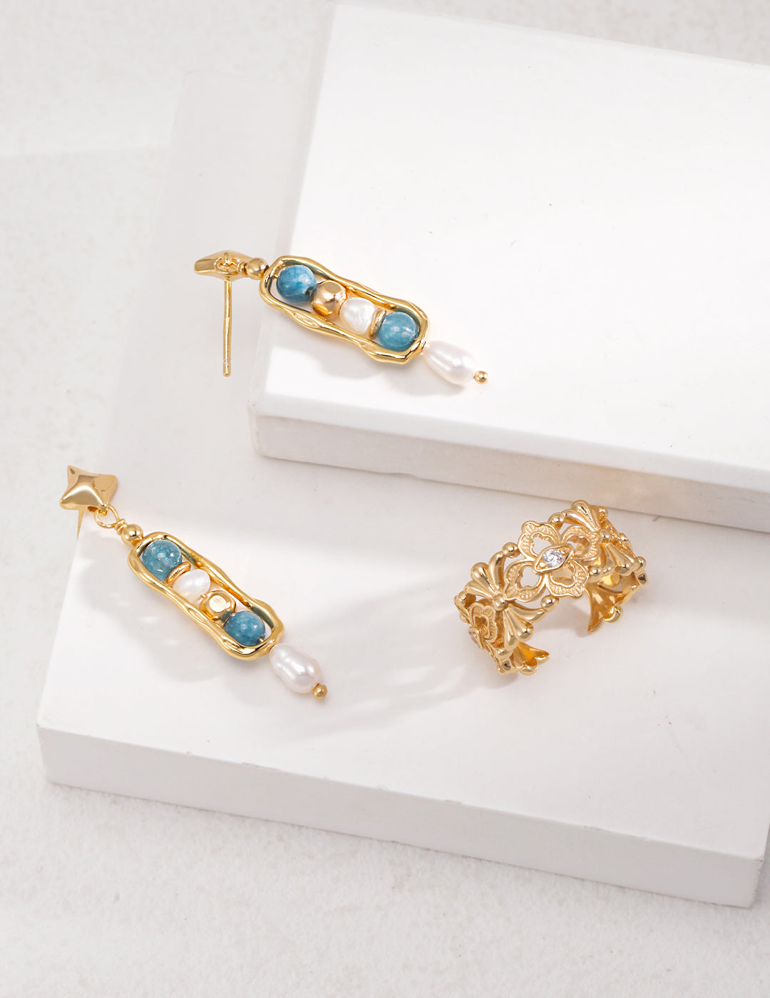 Shimmering gold jewelry set with beautiful blue gemstones - dangling earrings and a luxurious ring.