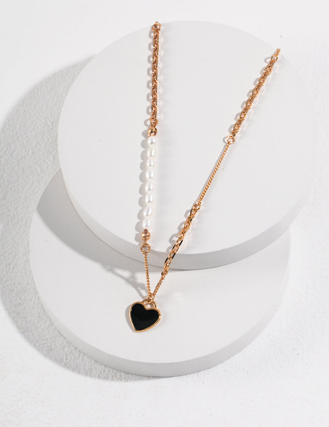 Elegant gold chain necklace, accented by gold black enamel heart pendant and freshwater pearls.