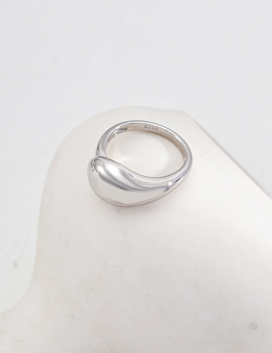 A sleek silver ring with a polished finish and a gracefully curved top, embodying contemporary elegance.