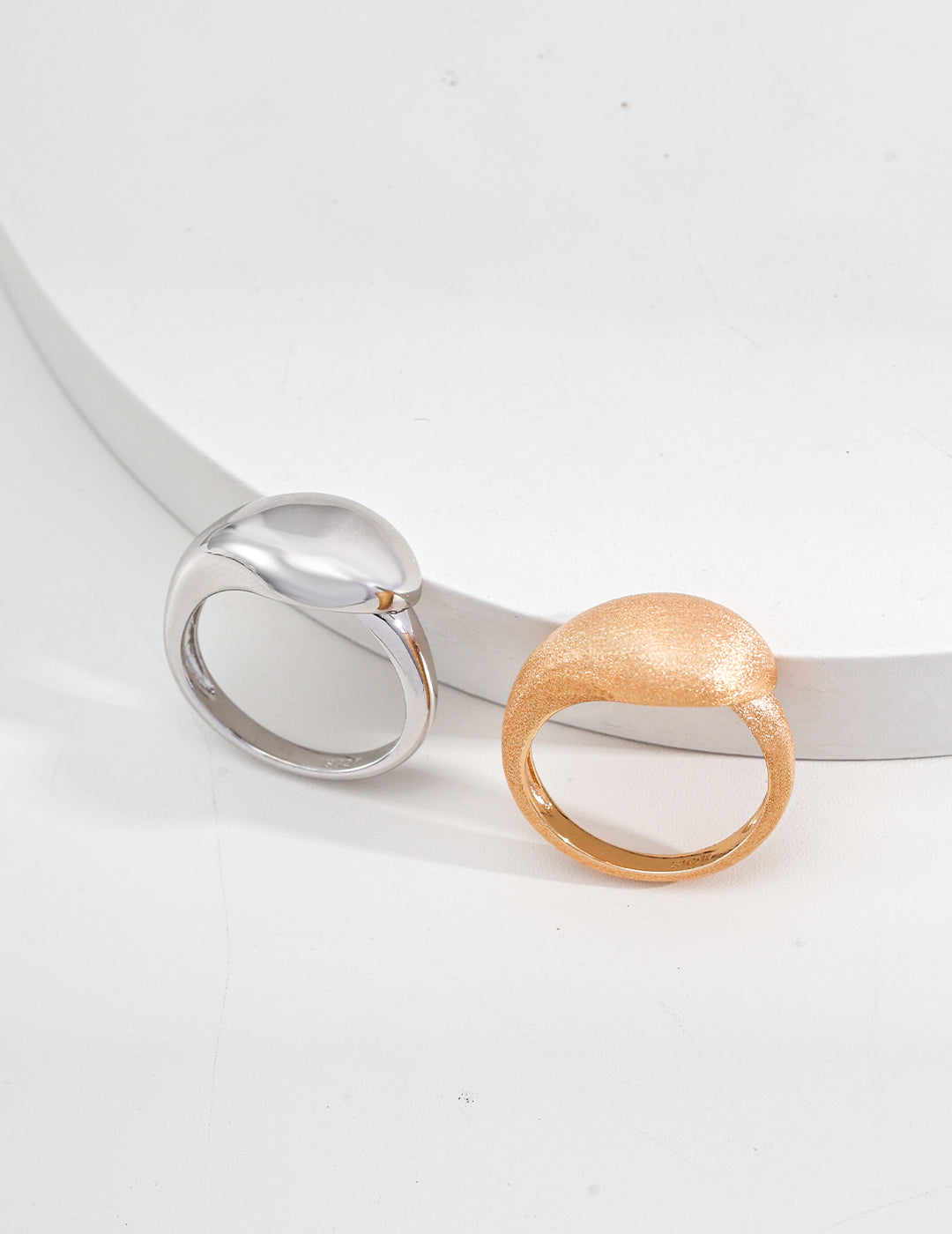 A pair of smooth, matte rings featuring gold and silver, showcasing a modern and elegant design.