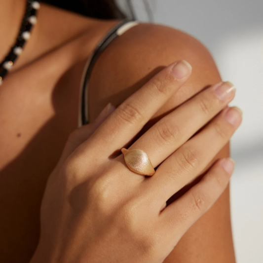 Close-up of a woman's hand adorned with a sleek and contemporary gold ring.