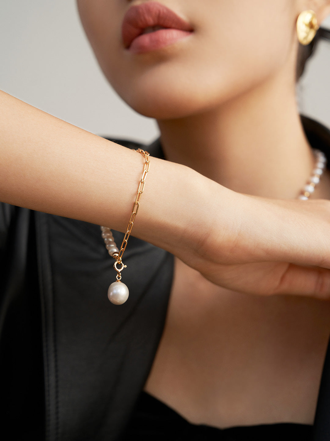 A woman wearing a gold chain pearl bracelet, adding elegance and sophistication to her outfit.