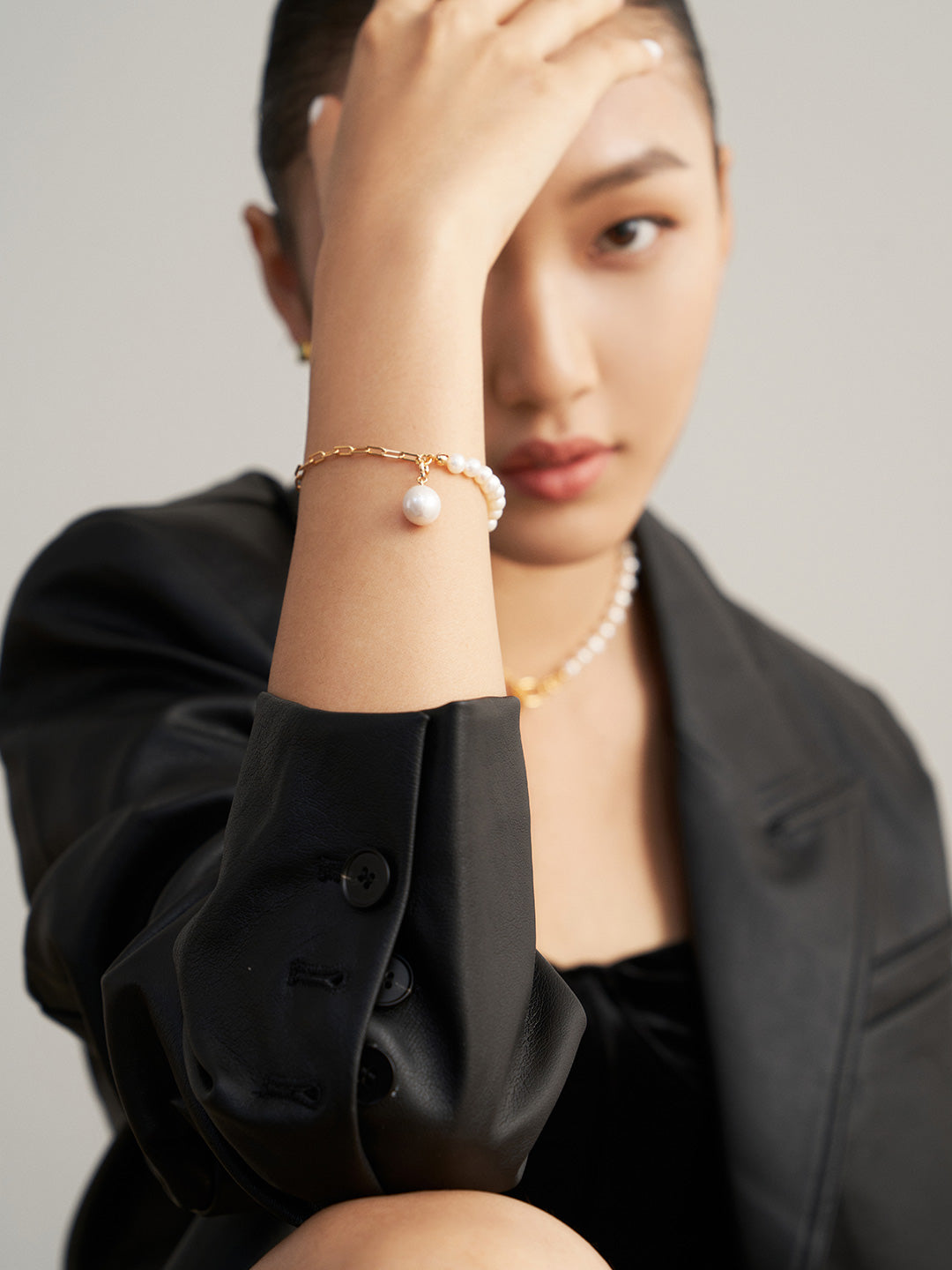 A stylish woman in a black leather jacket wearing a pearl bracelet that exudes elegance and sophistication.