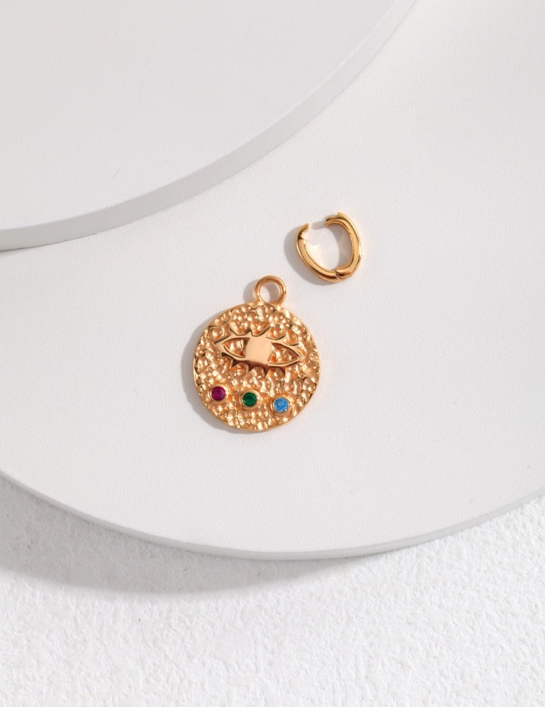  A gold charm showcasing a heart and rainbow design, accented with an evil eye pendant for added significance.