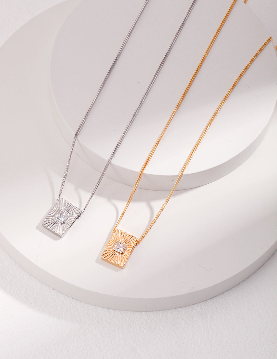 Elegant silver and gold necklaces featuring square pendants.