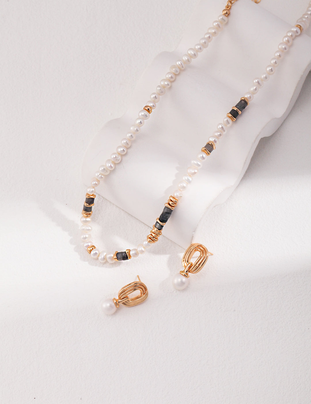 Elegant jewelry set featuring a gold necklace adorned with freshwater pearls and labradorite, with matching pearl earrings.