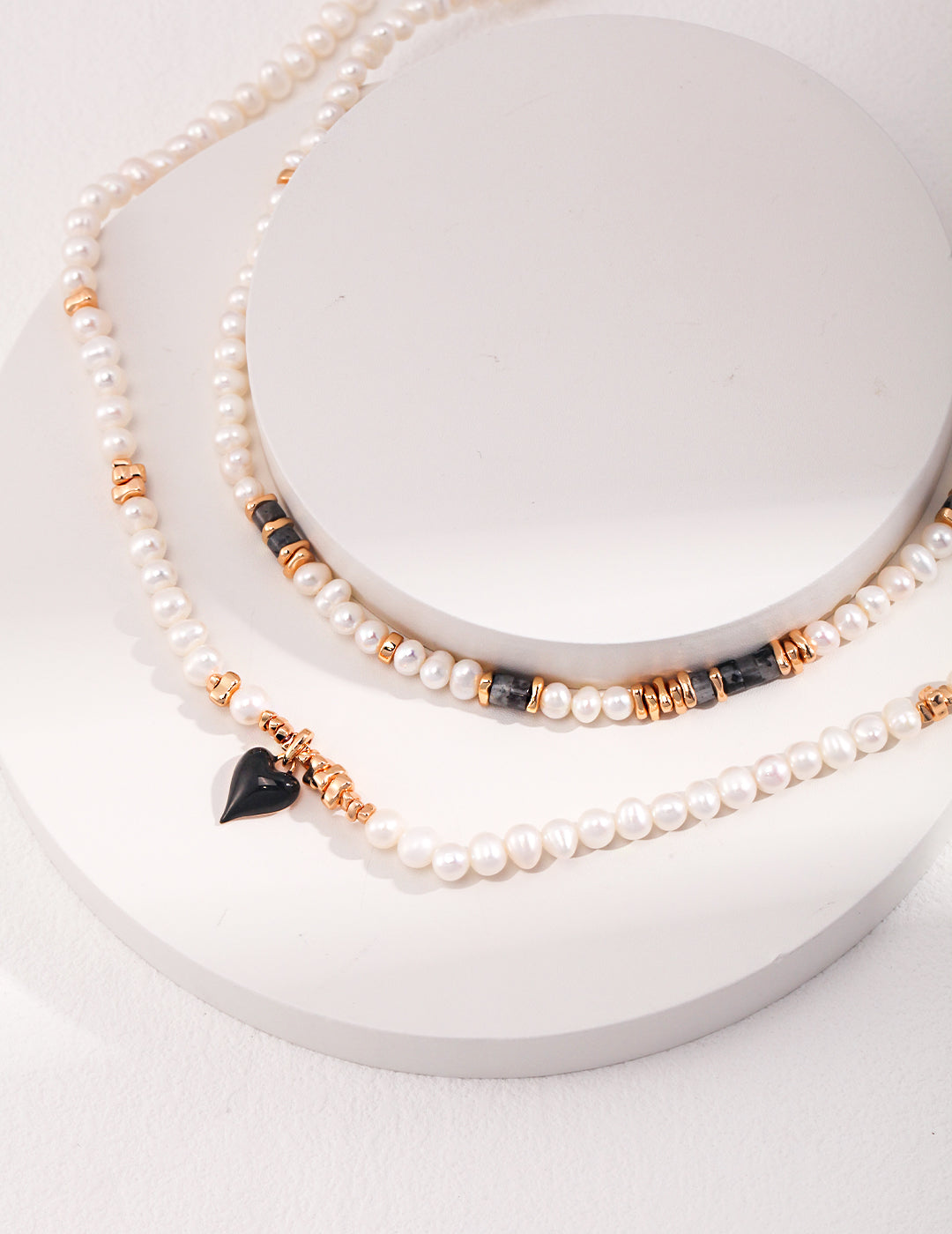 Gold necklace with freshwater pearls and black enamel heart pendant.