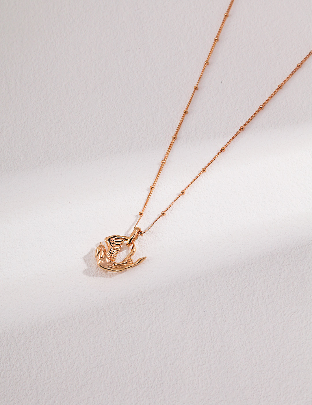 Gold necklace with a delicate bird pendant, perfect for adding a touch of elegance and nature to your outfit.