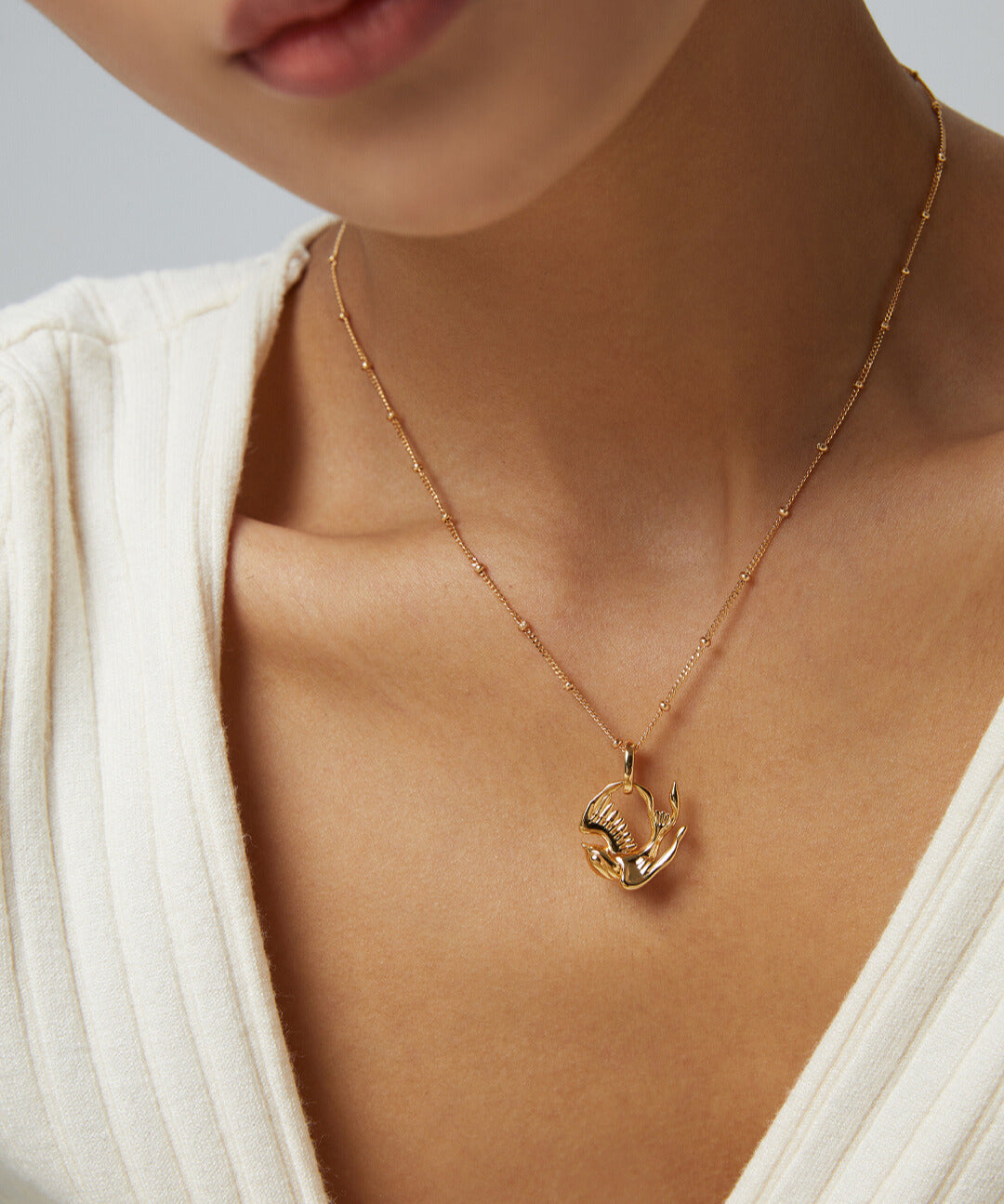 Model in gold plated necklace with robin pendant.