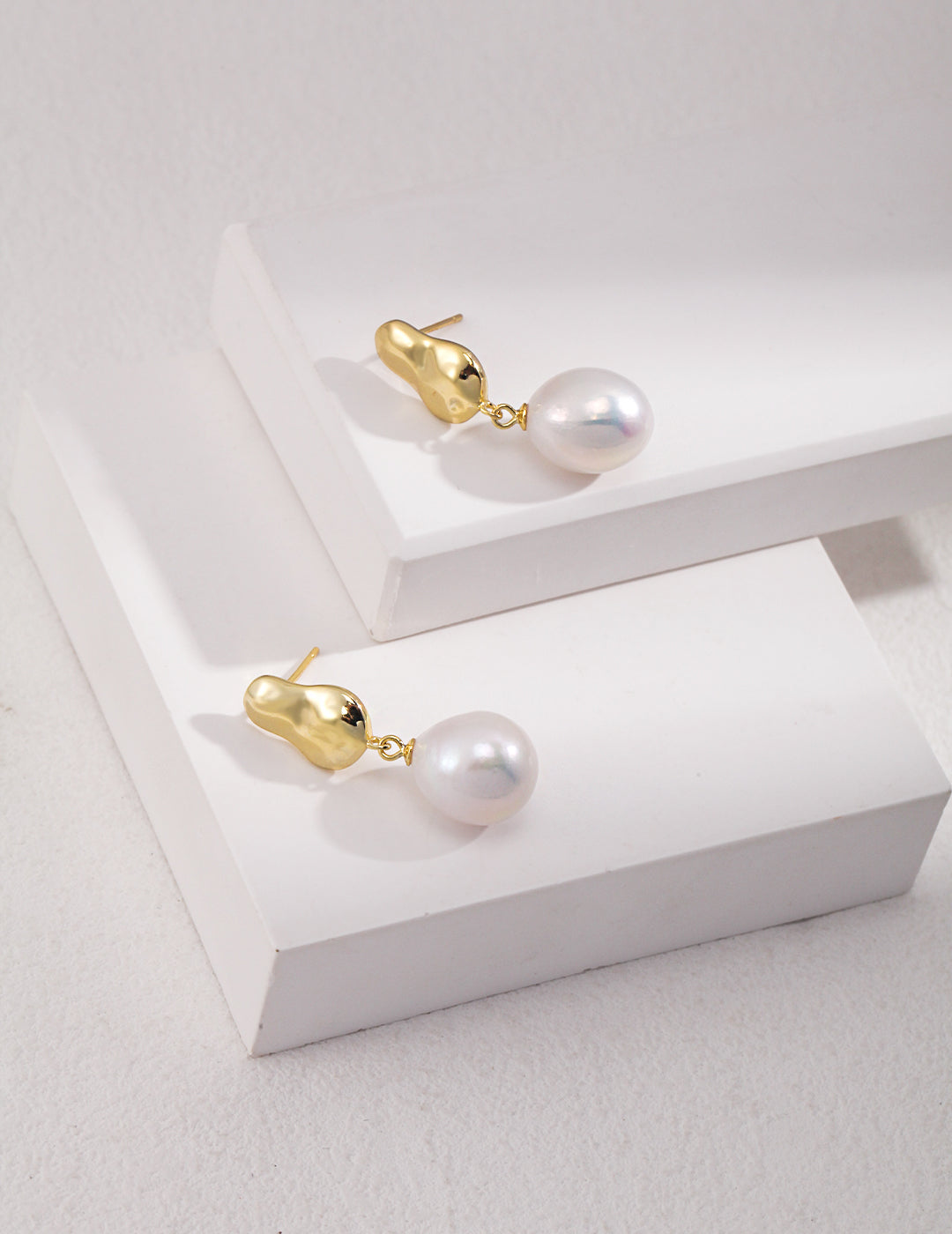 Dangling gold-plated earrings adorned with white baroque pearls.