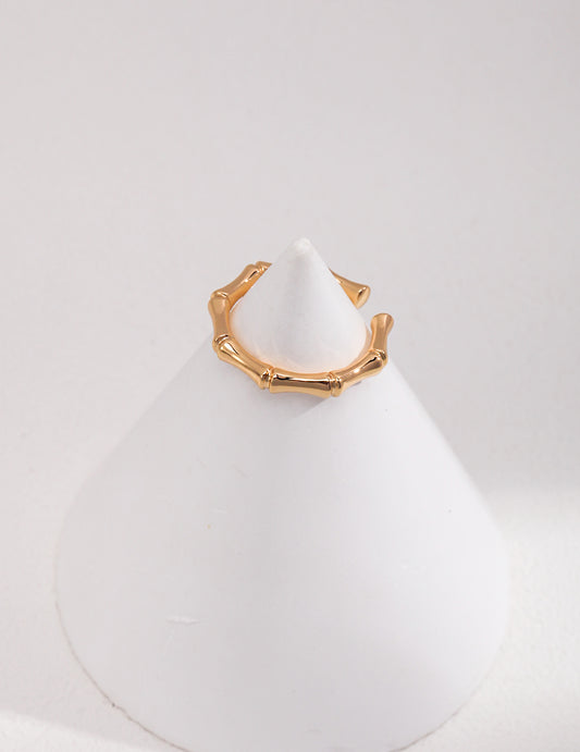 A stunning gold bamboo inspired ring displayed on a white cone.