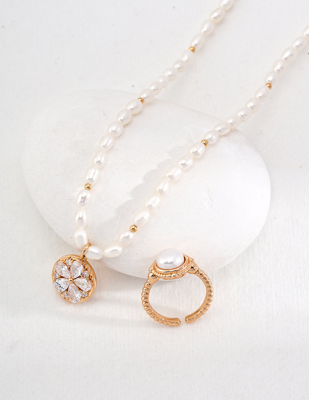 Pearl necklace and ring set on white stone, elegant jewelry for a special occasion.