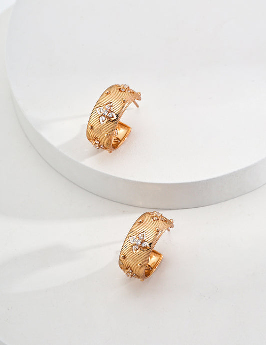 Mezuille Florence wide gold hoops with floral stone accents and linen texture on a clean white background.