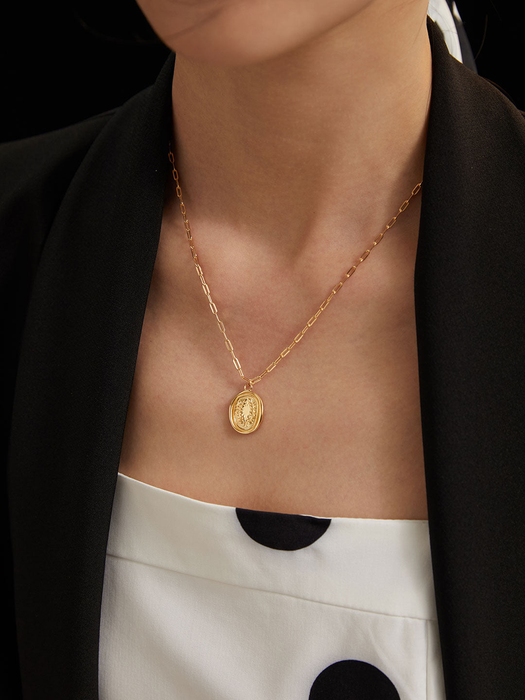 A woman wearing a gold plated coin pendant necklace, adding elegance and charm to her outfit.