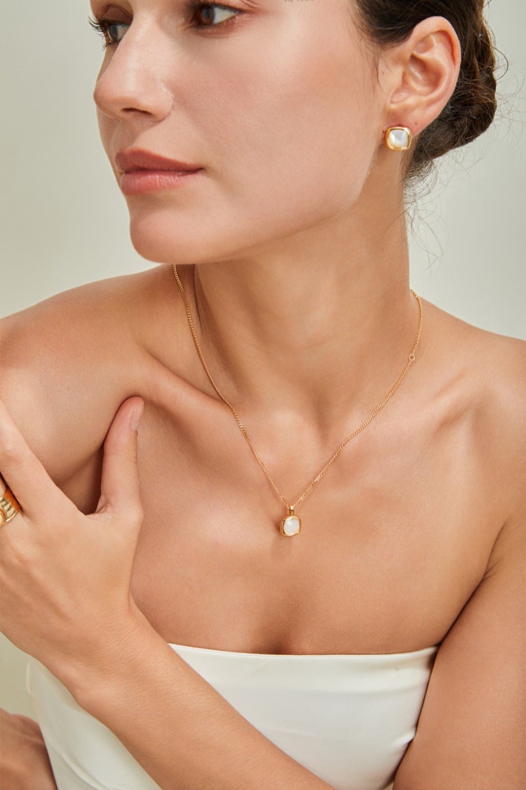 Elegant woman in a white dress, complemented by a stunning gold necklace, radiating beauty and sophistication.