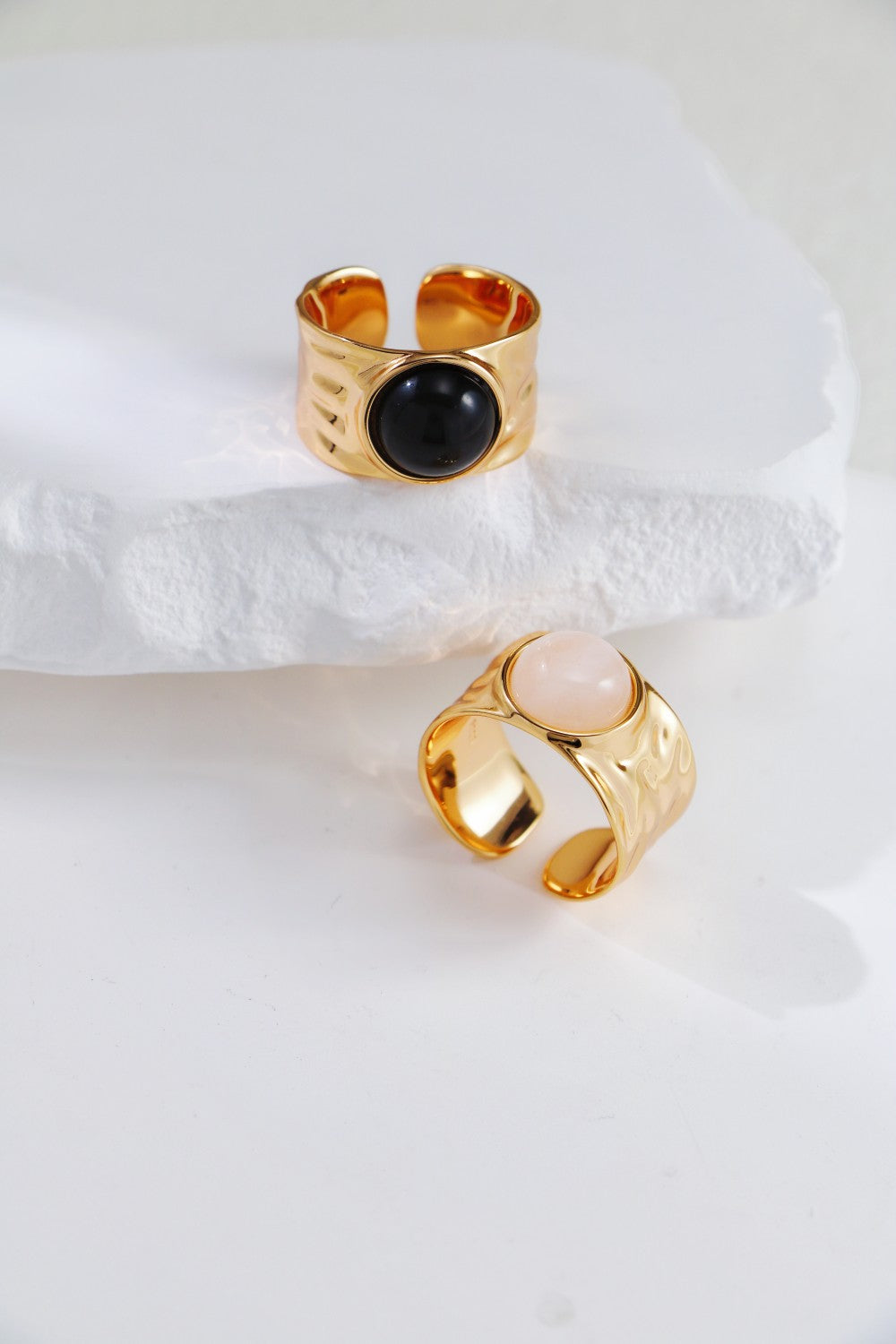 Two elegant gold rings showcasing bold band, with bold designs incorporating black agate and clear quartz accents.