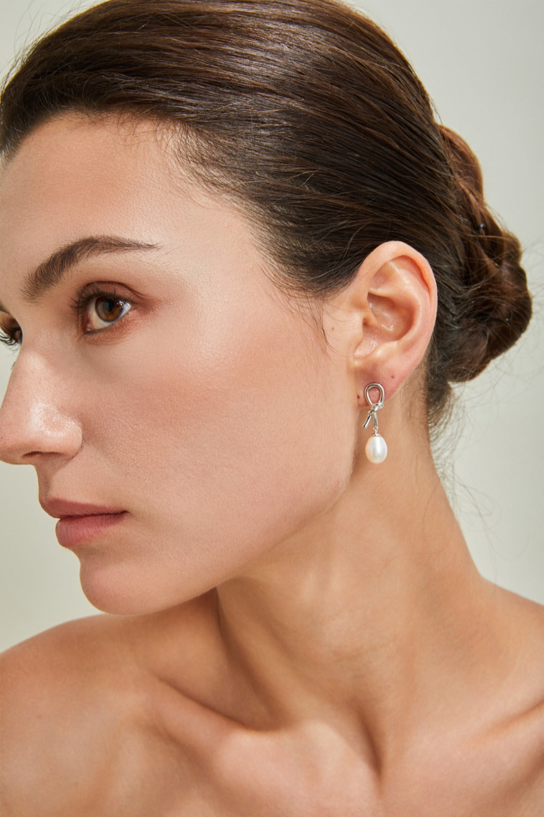 A close-up of a woman featuring a stunning pearl earring, highlighting her sophisticated look.