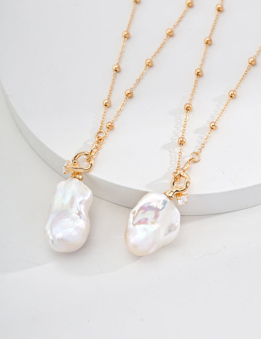 Two exquisite white pearls hanging from a gold chain, embodying sophistication in a stunning freshwater pearl necklace.