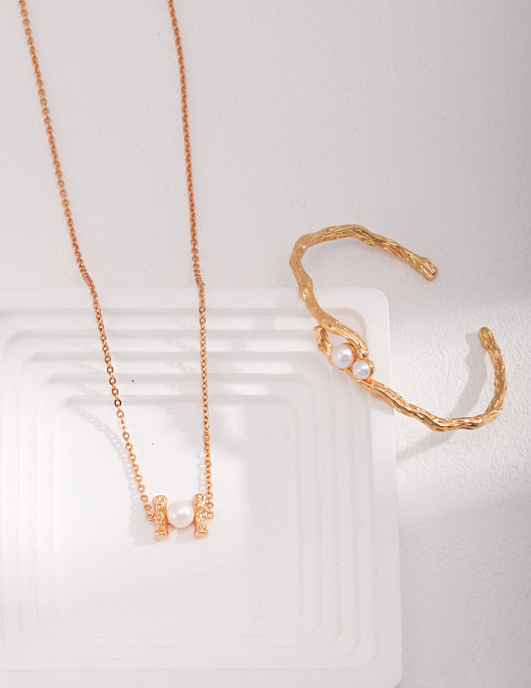 Luxurious gold necklace and bangle displayed on white plate.