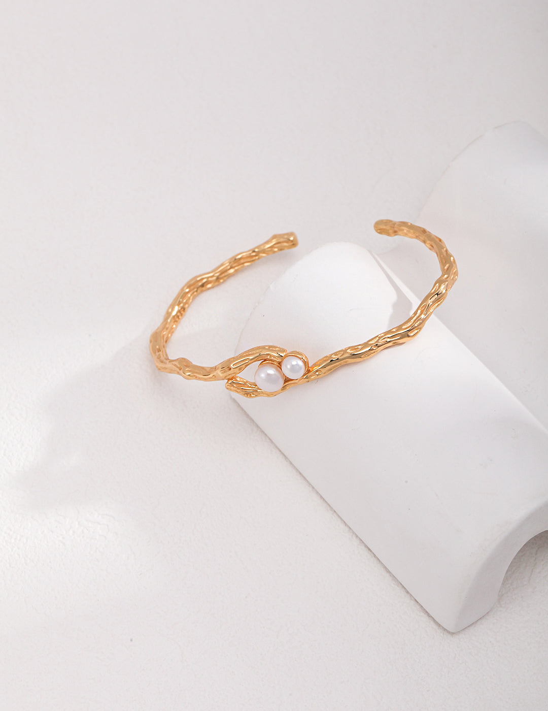 A stunning gold torque bangle with freshwater pearls delicately placed on it.