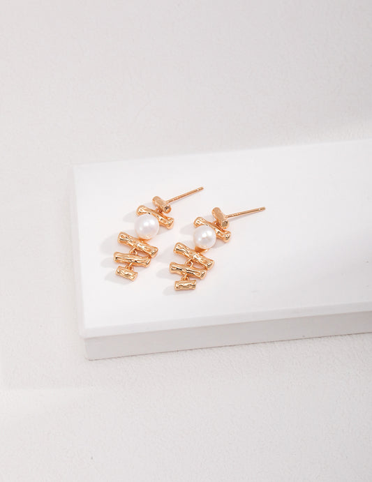 Stylish gold earrings featuring freshwater pearls on white base.