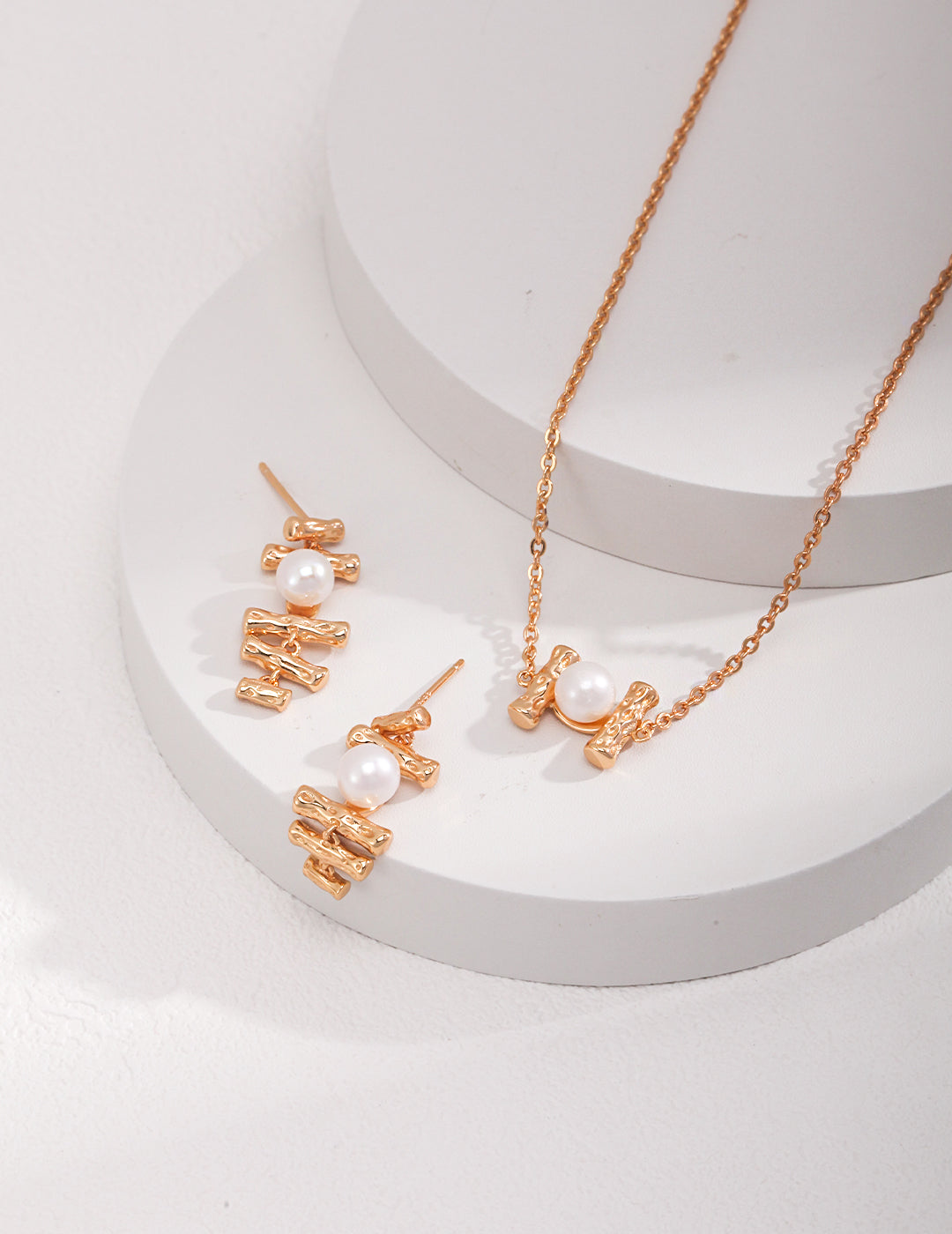 A stunning gold necklace and earrings set with freshwater pearls, elegantly displayed on a white surface.