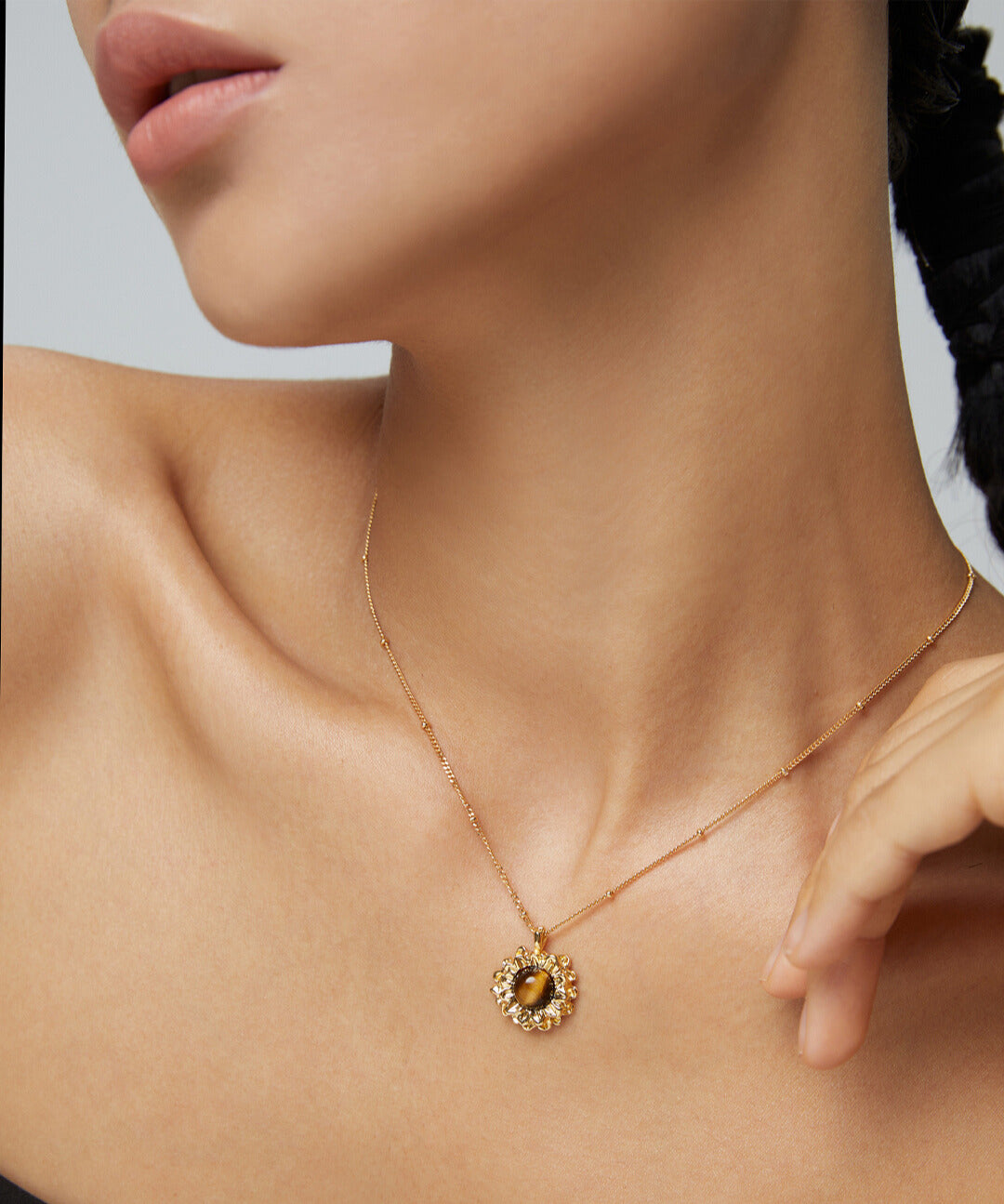 Elegant lady with tiger's eye pendant on gold chain.