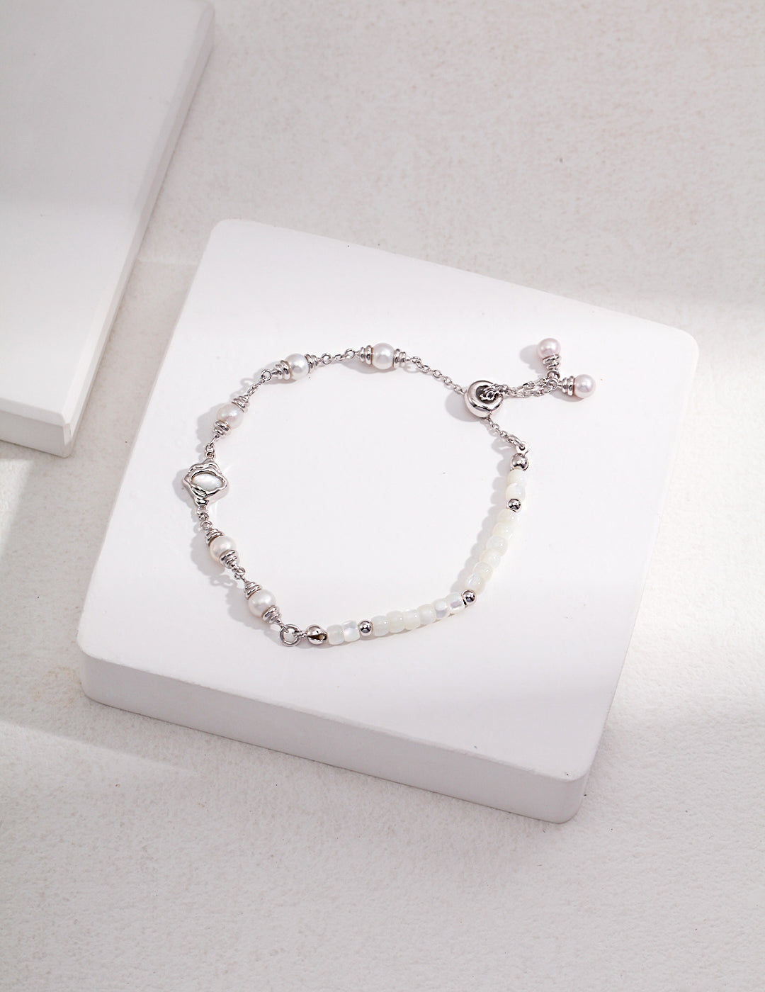 Stylish silver bracelet adorned with white nacre, silk shells, and pearls.