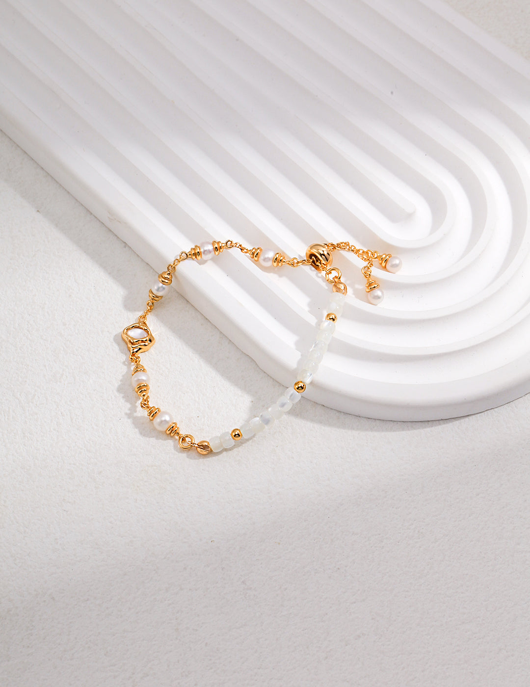 A stunning gold bracelet adorned with nacre, silk shells, and freshwater pearls.