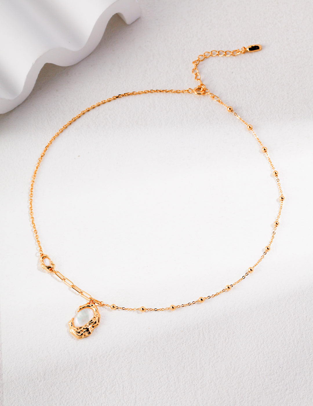 Elegant gold necklace featuring pendant made of mother of pearls.