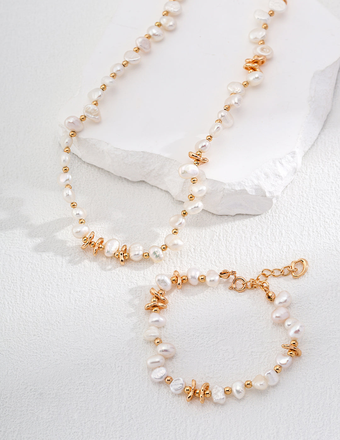 Enhance your style with a captivating gold necklace and bracelet featuring exquisite white pearls, a symbol of timeless beauty.