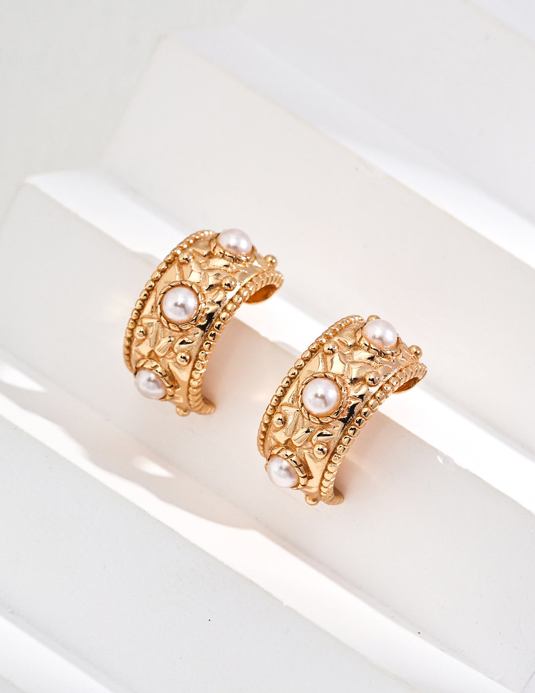 Beautiful gold tone earrings in a hoop design, embellished with shell pearls for a stylish and refined appearance.