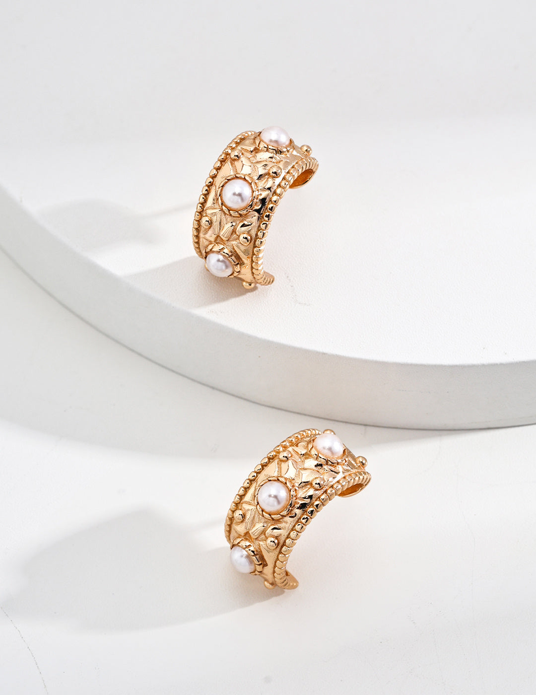 Chic gold tone hoop earrings embellished with shell pearls, a stylish accessory that enhances any jewelry collection effortlessly.