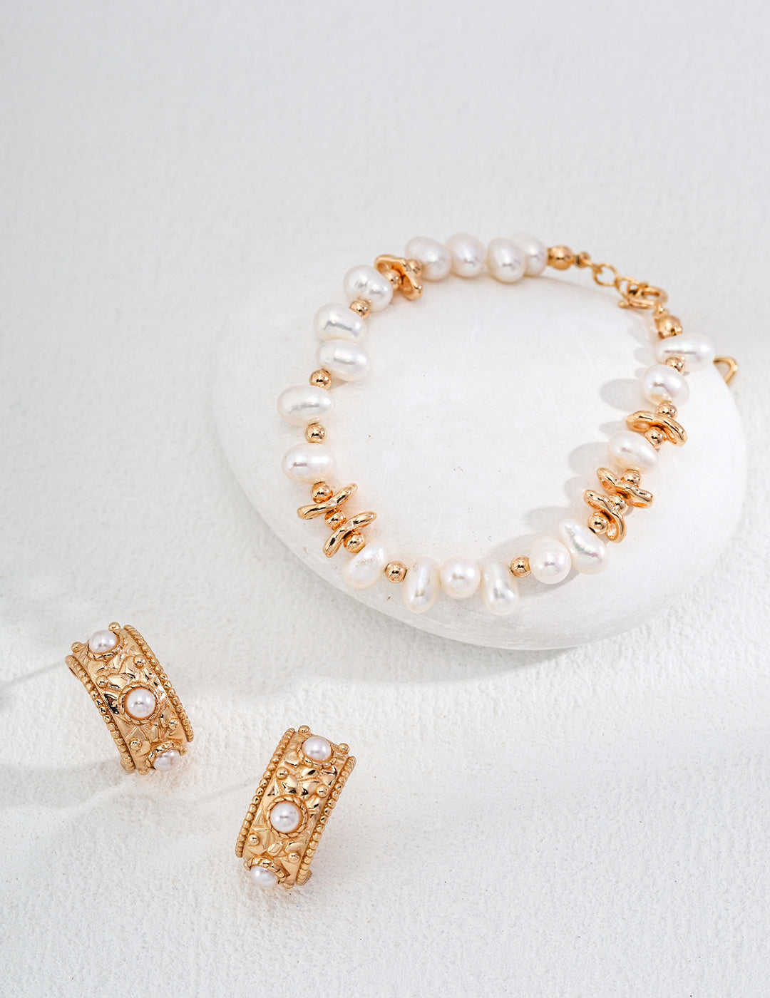 Elegant gold hoops and a matching bracelet adorned with lustrous pearls, showcasing timeless sophistication and style.