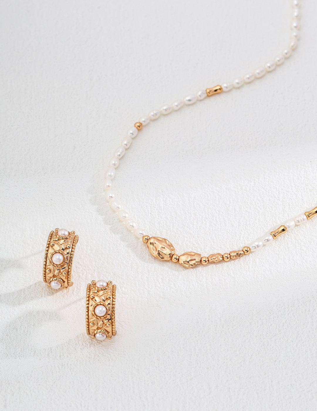 Stunning gold jewelry set featuring a matching necklace and pearl hoop earrings, ideal for adding elegance to any outfit.