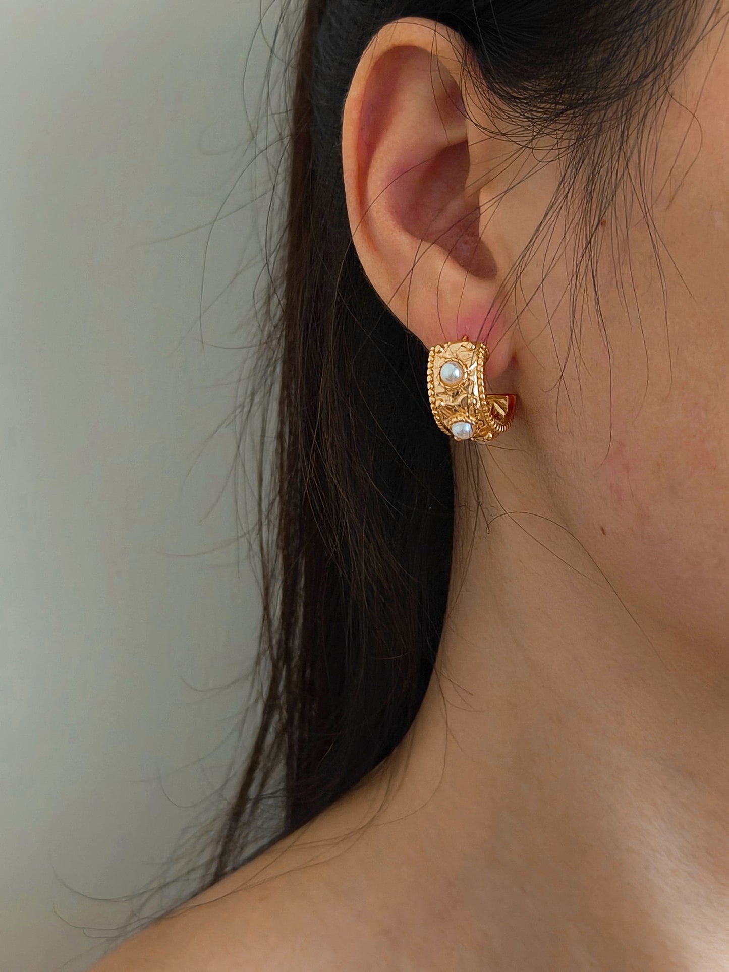 A woman adorned with elegant gold earrings, showcasing her stylish accessories.
