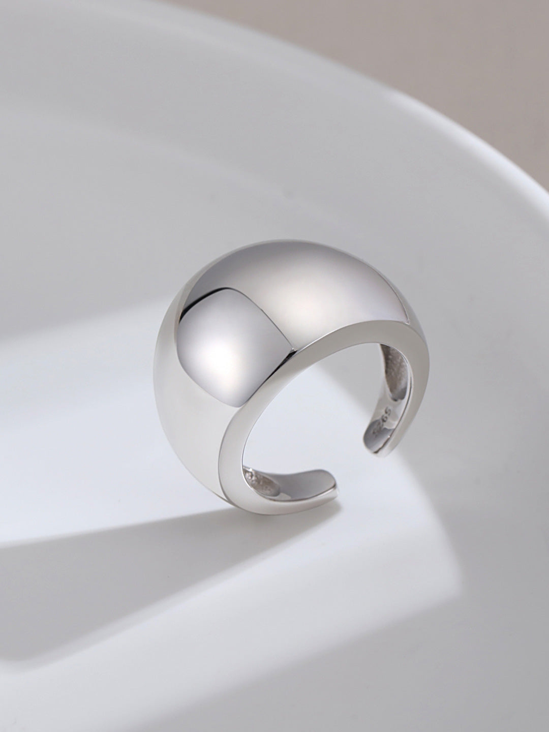 Silver chunky dome ring resting on white plate.