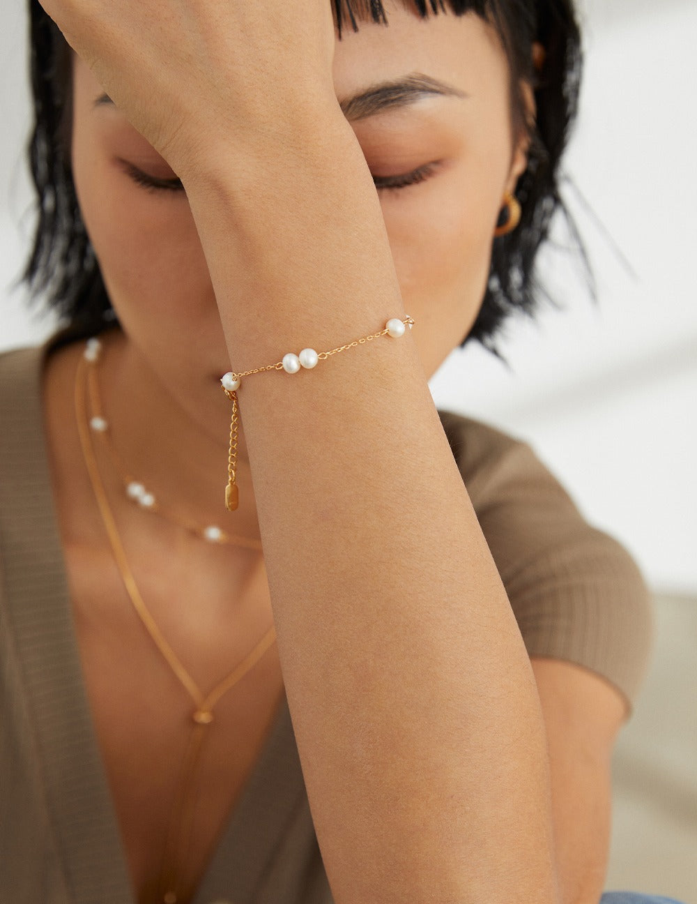 Woman wearing a delicate pearl bracelet and necklace from Mezuille.