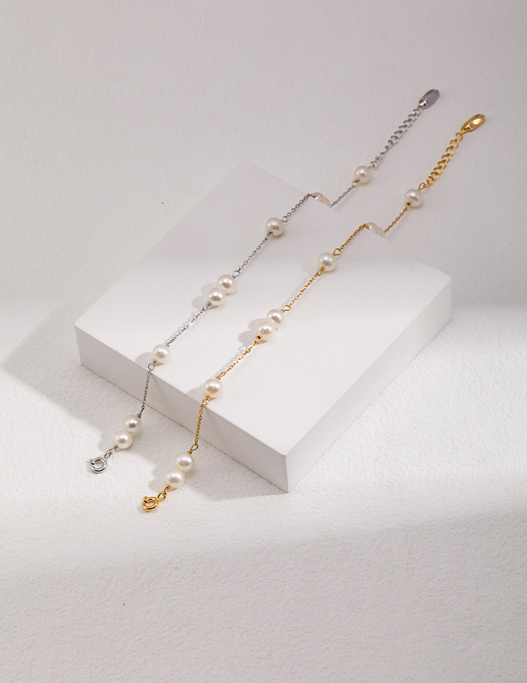 Two pearl chain bracelets from Mezuille on a white stand.