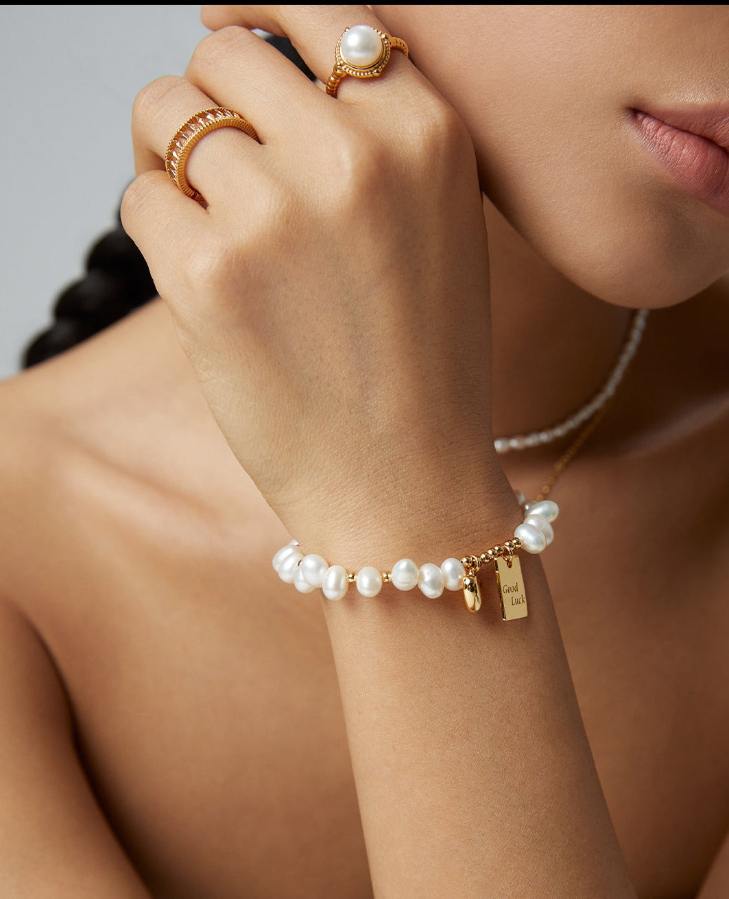 A woman showcasing a pearl bracelet and a gold ring, adding elegance and sophistication to her attire.