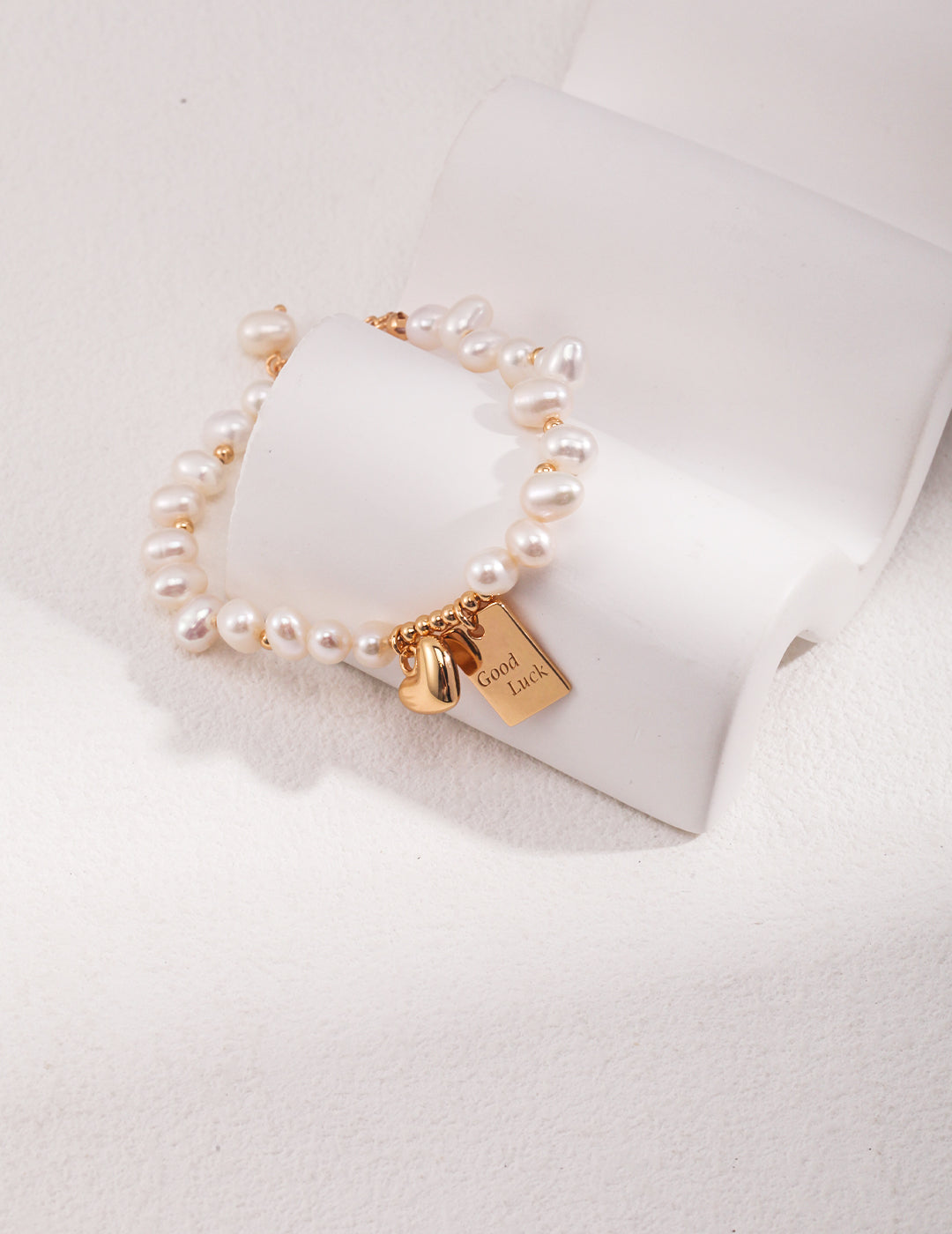 Elegant gold bracelet adorned with pearls and a charm, adding a touch of luxury to your look.