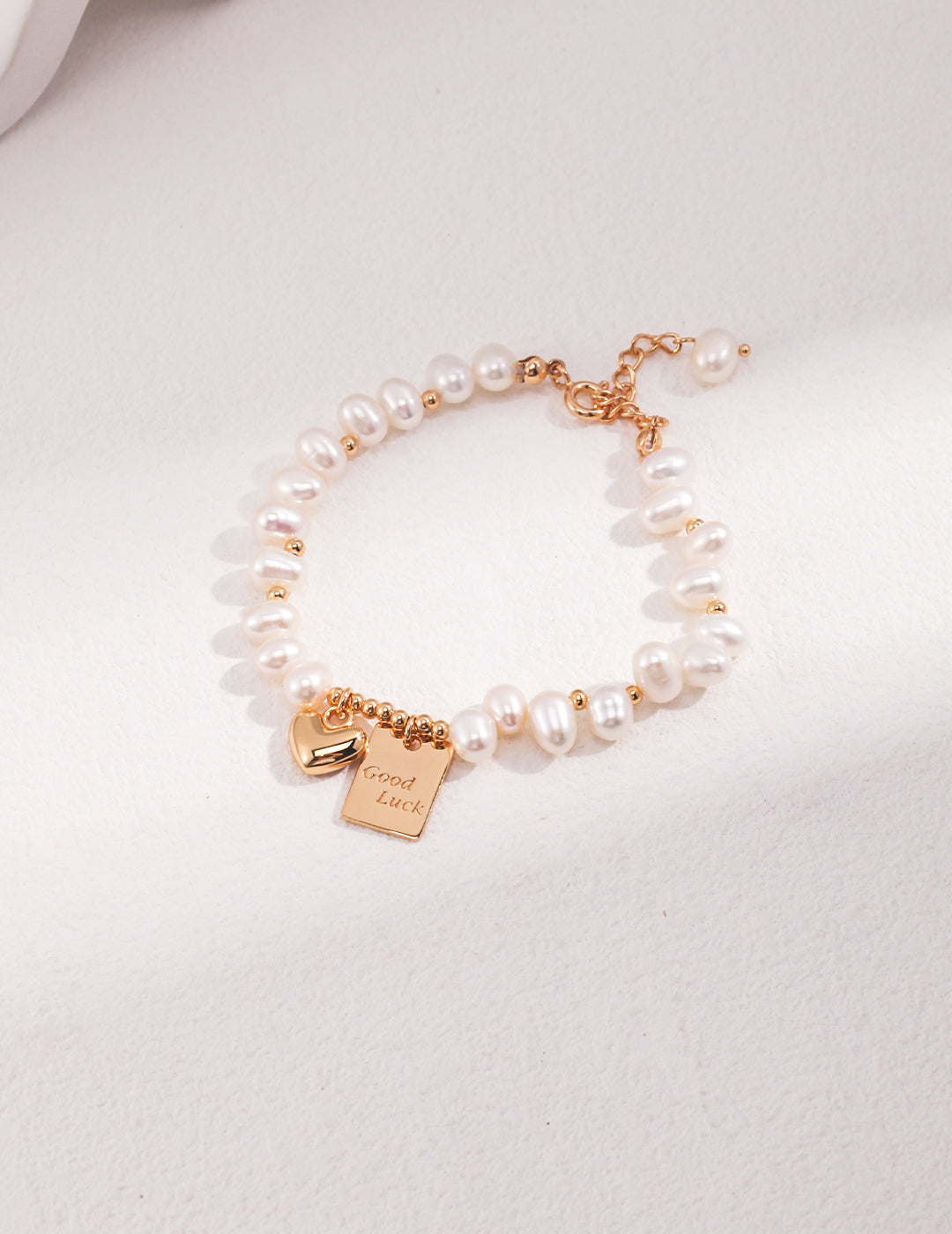 A gold plated bracelet with a heart charm and pearls, adding elegance and charm to any outfit.