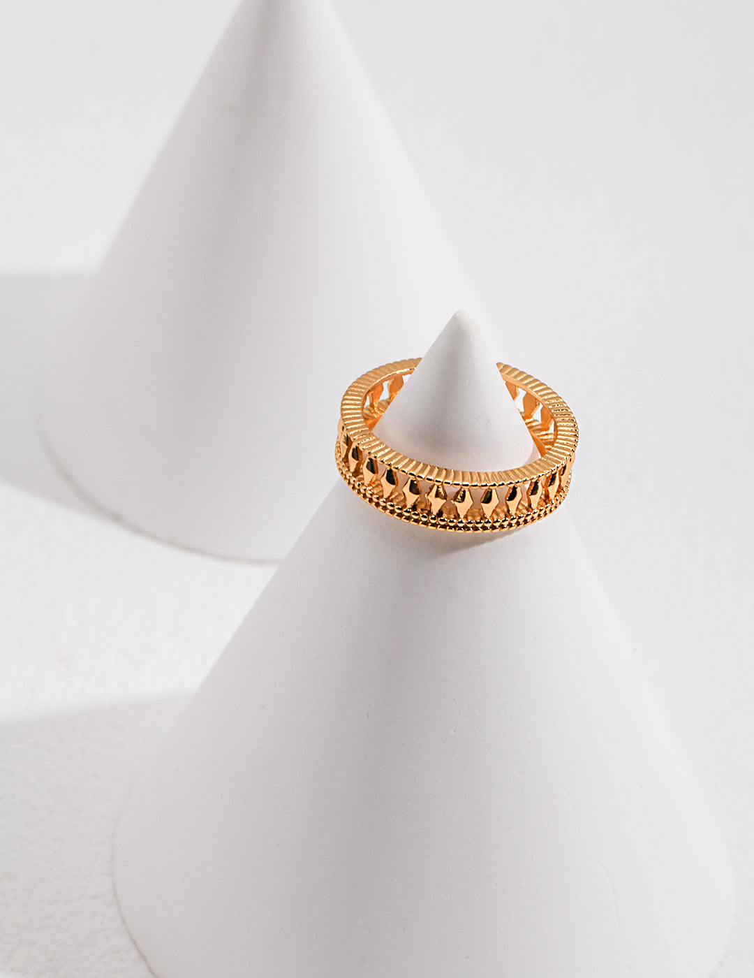 A gold ring resting on a white cone, showcasing elegance and simplicity.