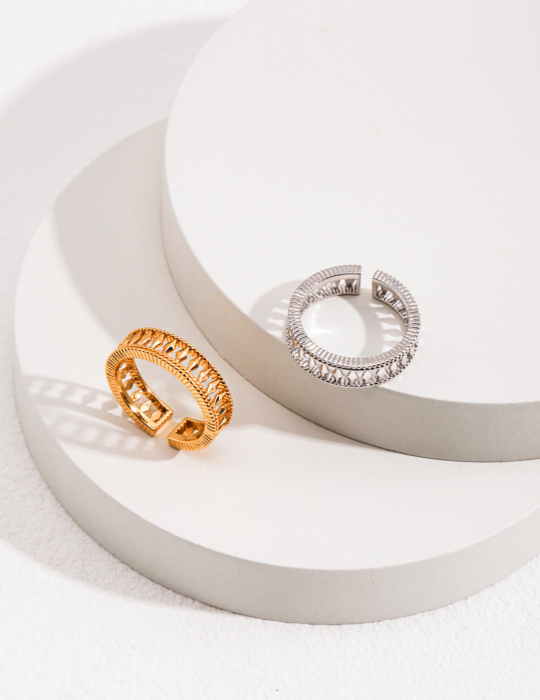 Two shiny hollow rings, one silver and one gold, on a white surface.