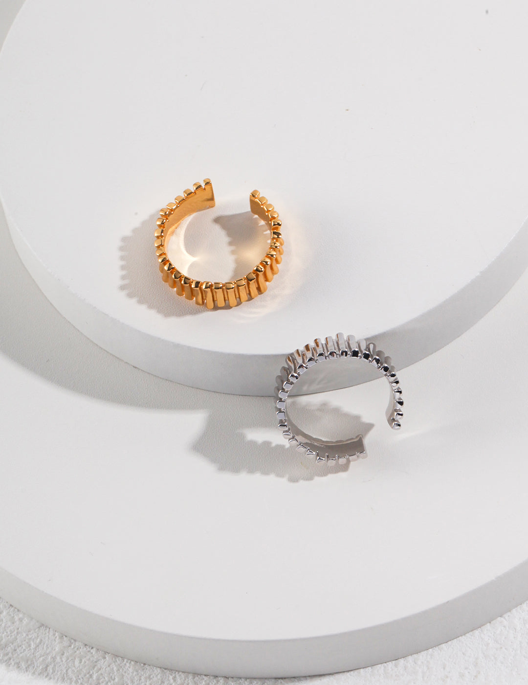 Stylish gold and silver rings with fine detailing displayed on a white surface.