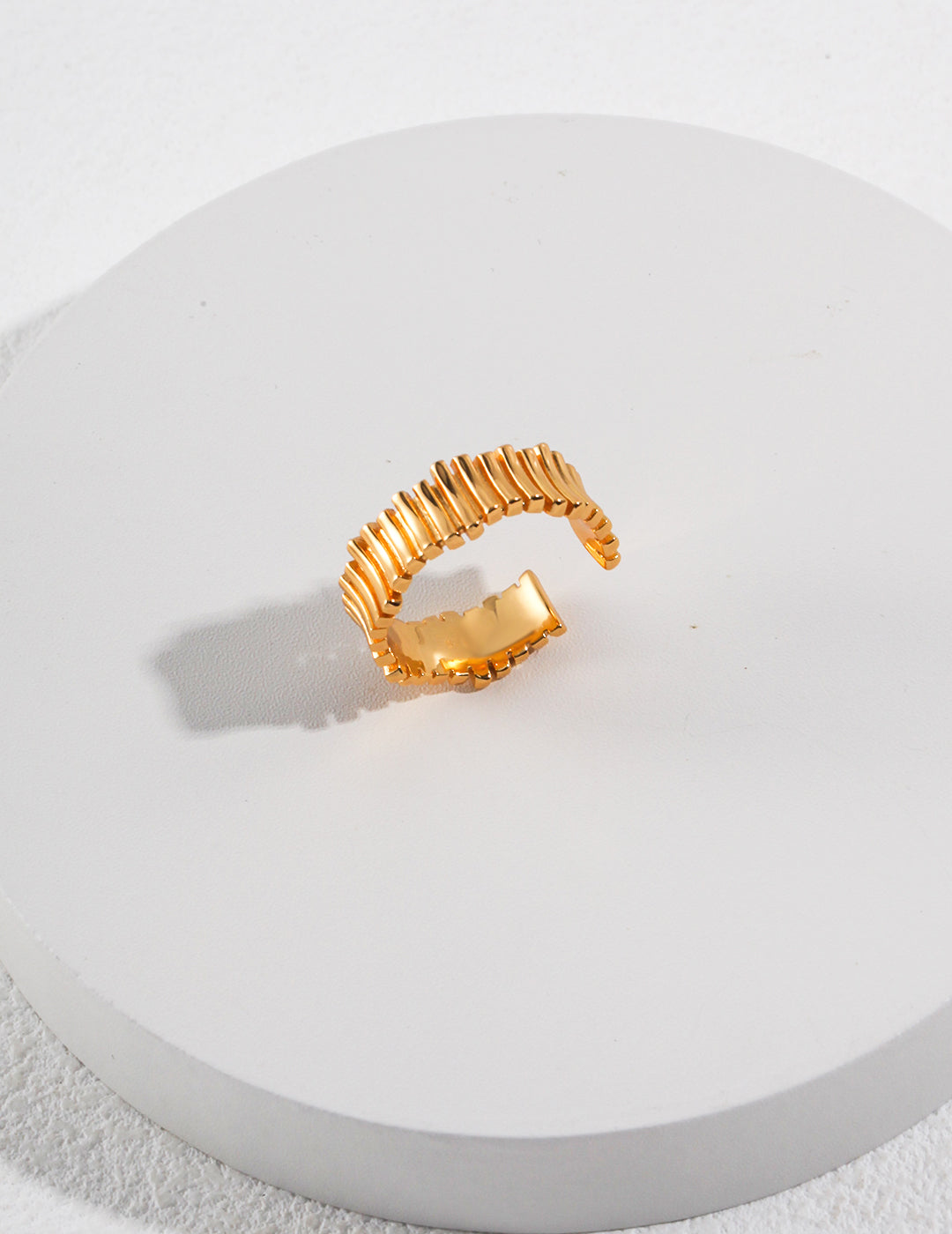 A fine gold ring placed on a white plate, showcasing its elegance and simplicity.