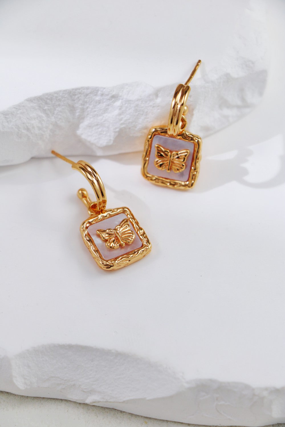 Gold-plated earrings with butterfly nacre, showcasing a striking look.