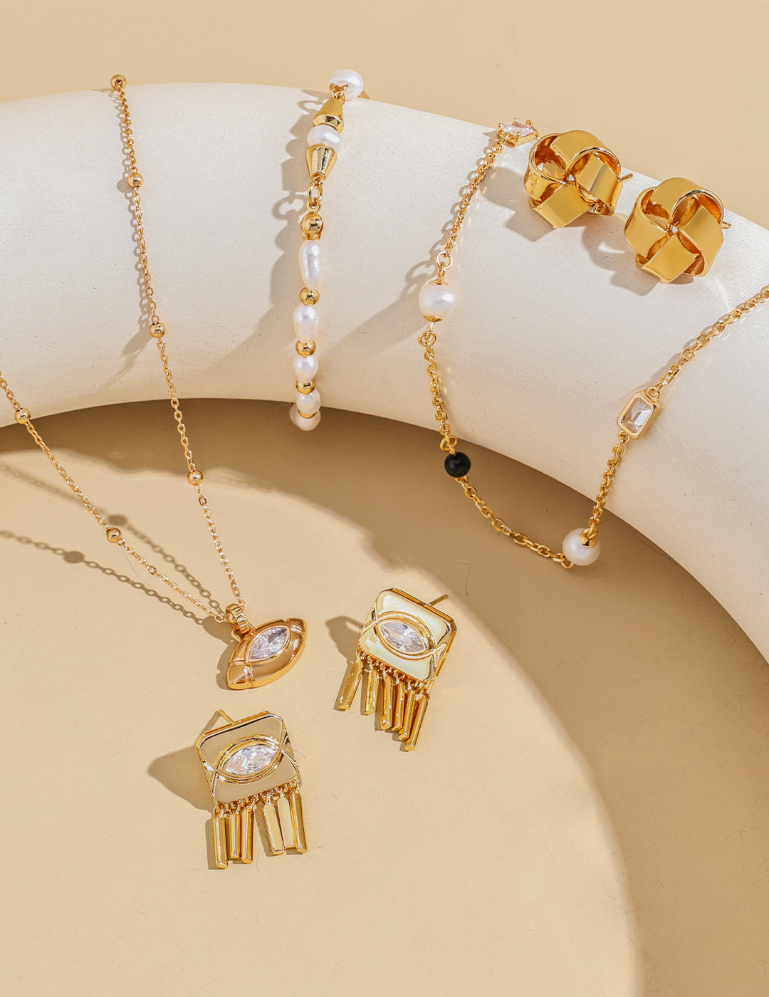 Shiny gold necklace, earrings, and bracelet arranged neatly on white table.